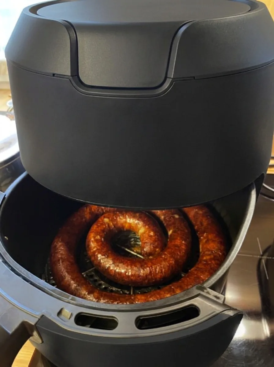 A kihúzott air fryer kosárban a készre sült kolbászcsiga